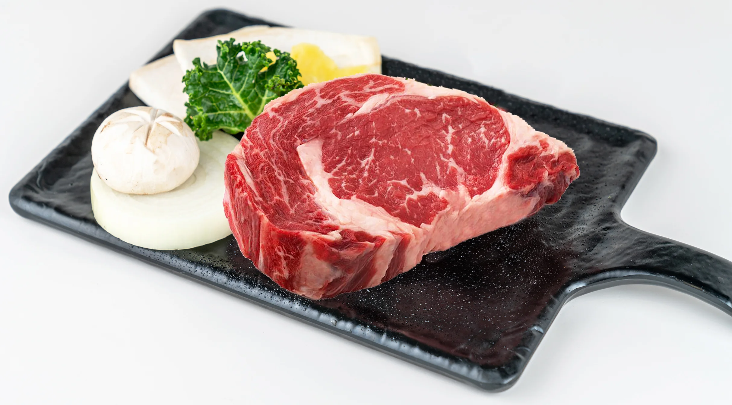 Raw ribeye steak on a sizzling platter