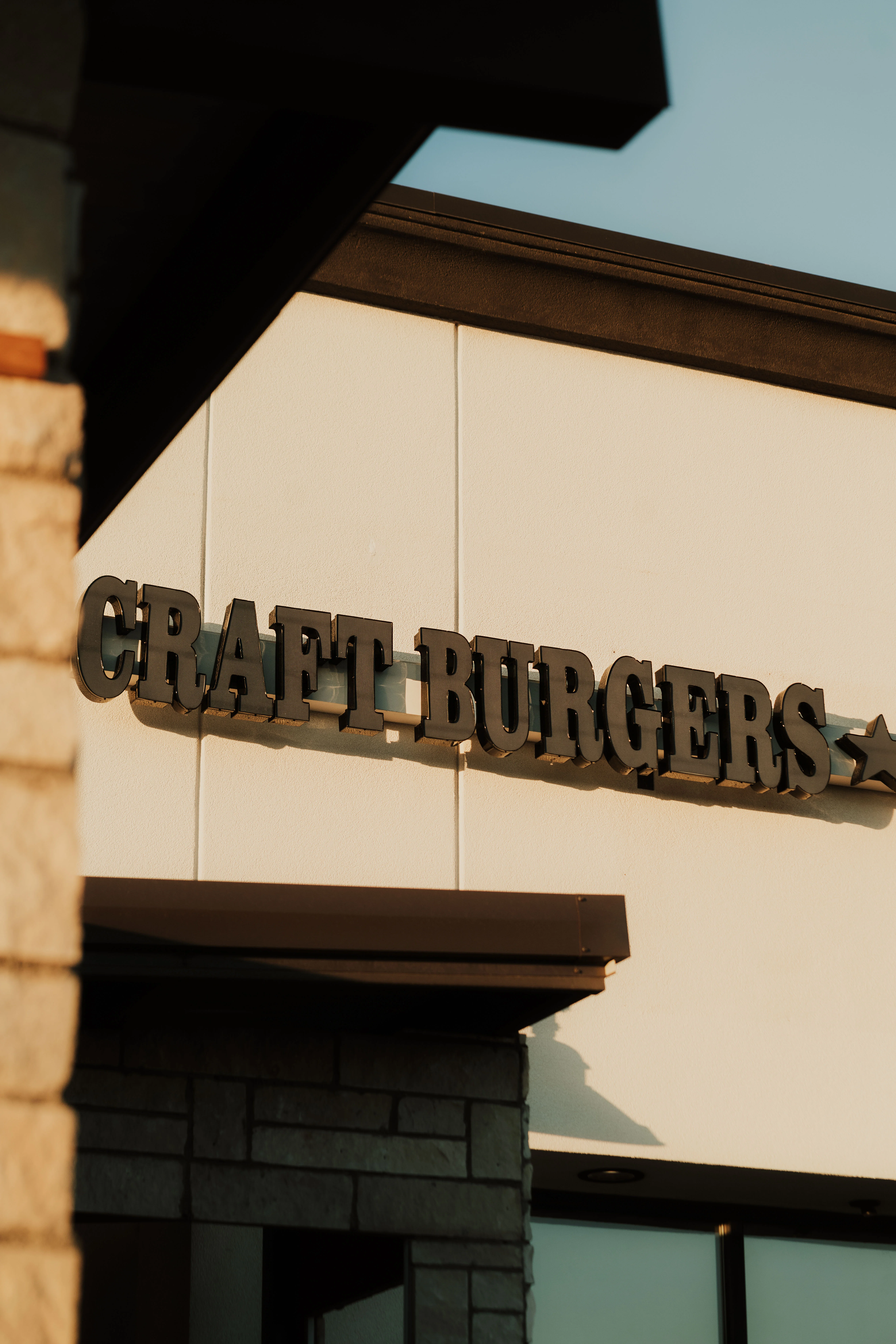 The entrance to a burger restaurant featuring large windows and a prominent sign.