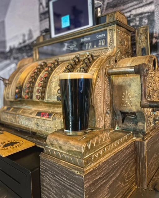 Vintage cash register with a dark beer glass