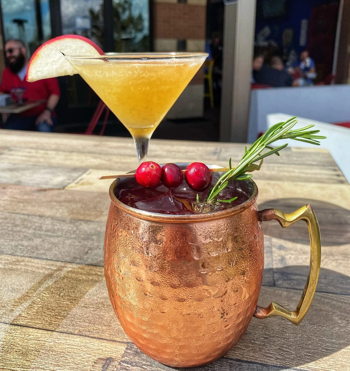Two cocktails: a copper mug drink and a martini with apple slice