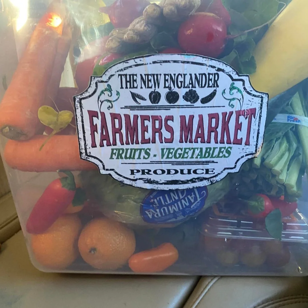 A container filled with an assortment of fresh fruits and vegetables, labeled as a farmers market produce.