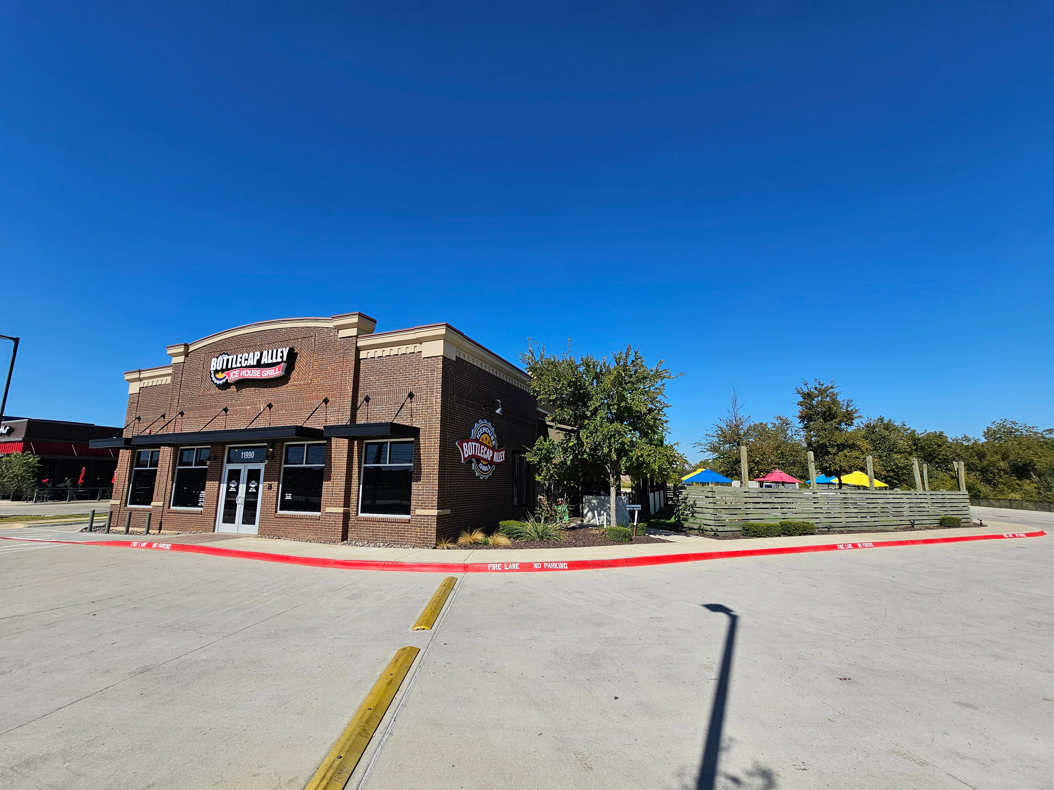 A brick building featuring prominent signage for a restaurant. The exterior has multiple windows and a clear blue sky in the background.