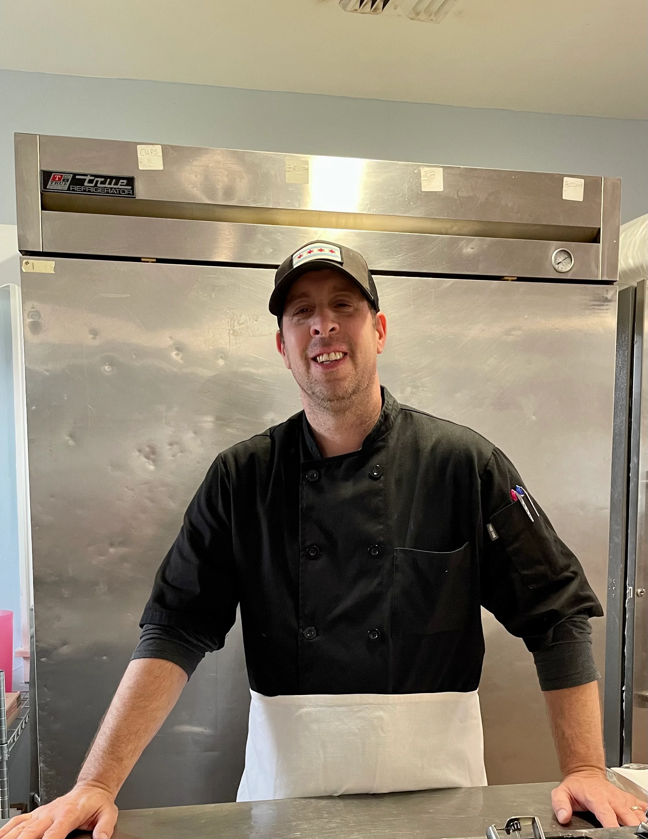 Chef smiling in a commercial kitchen with fresh ingredients