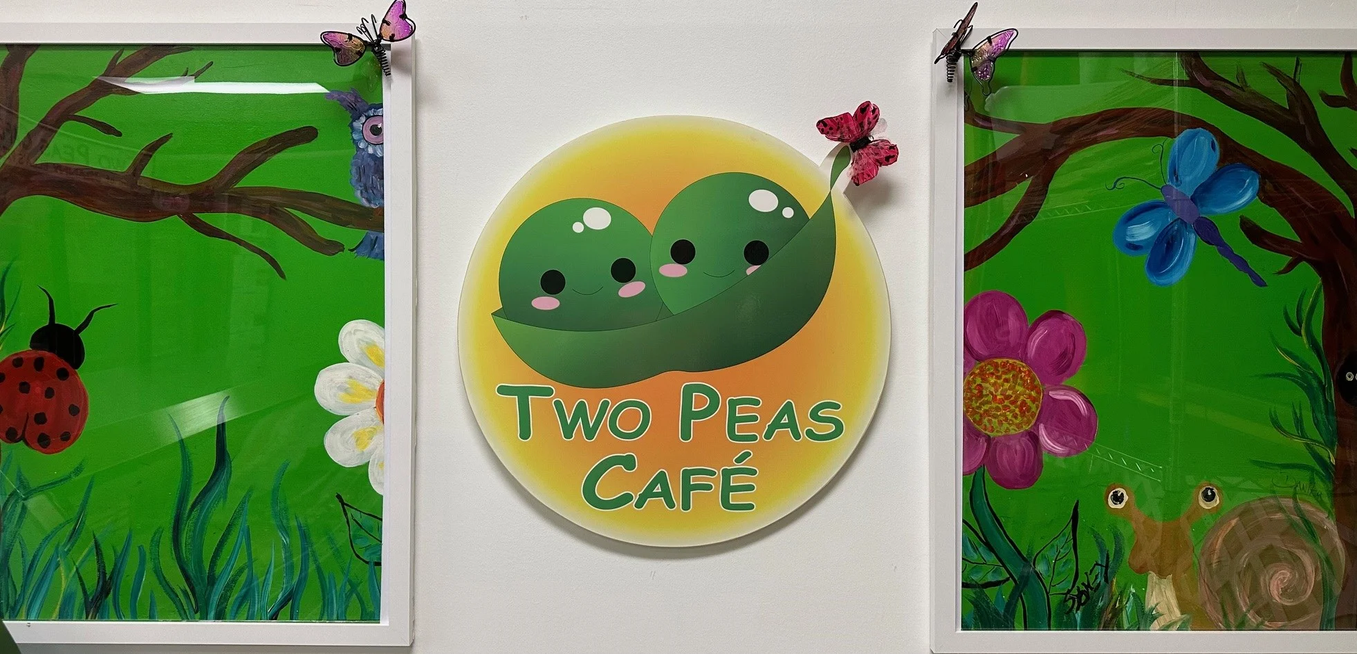 Colorful café sign for Two Peas Café with playful artwork