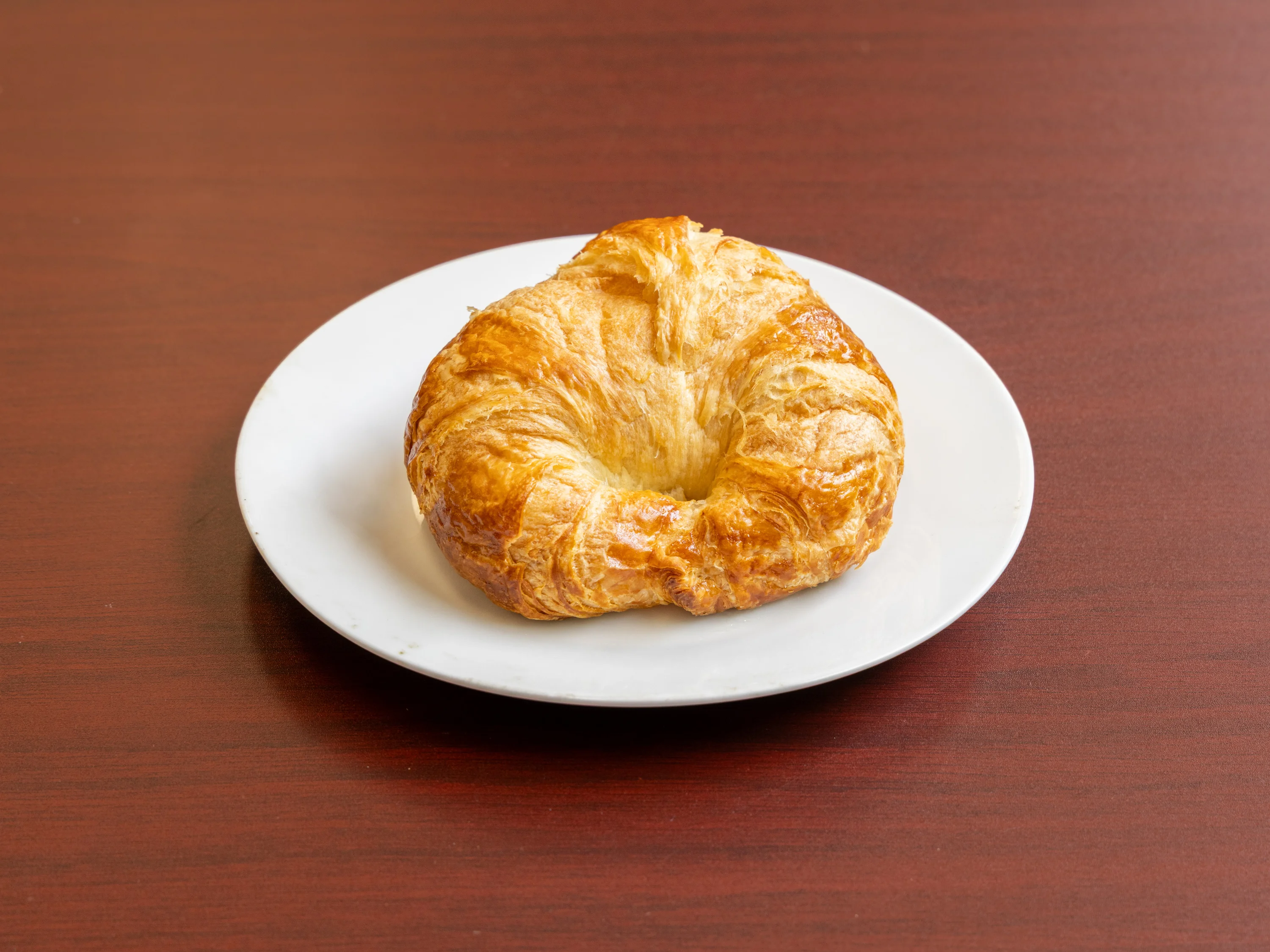 Freshly baked French croissant on a white plate