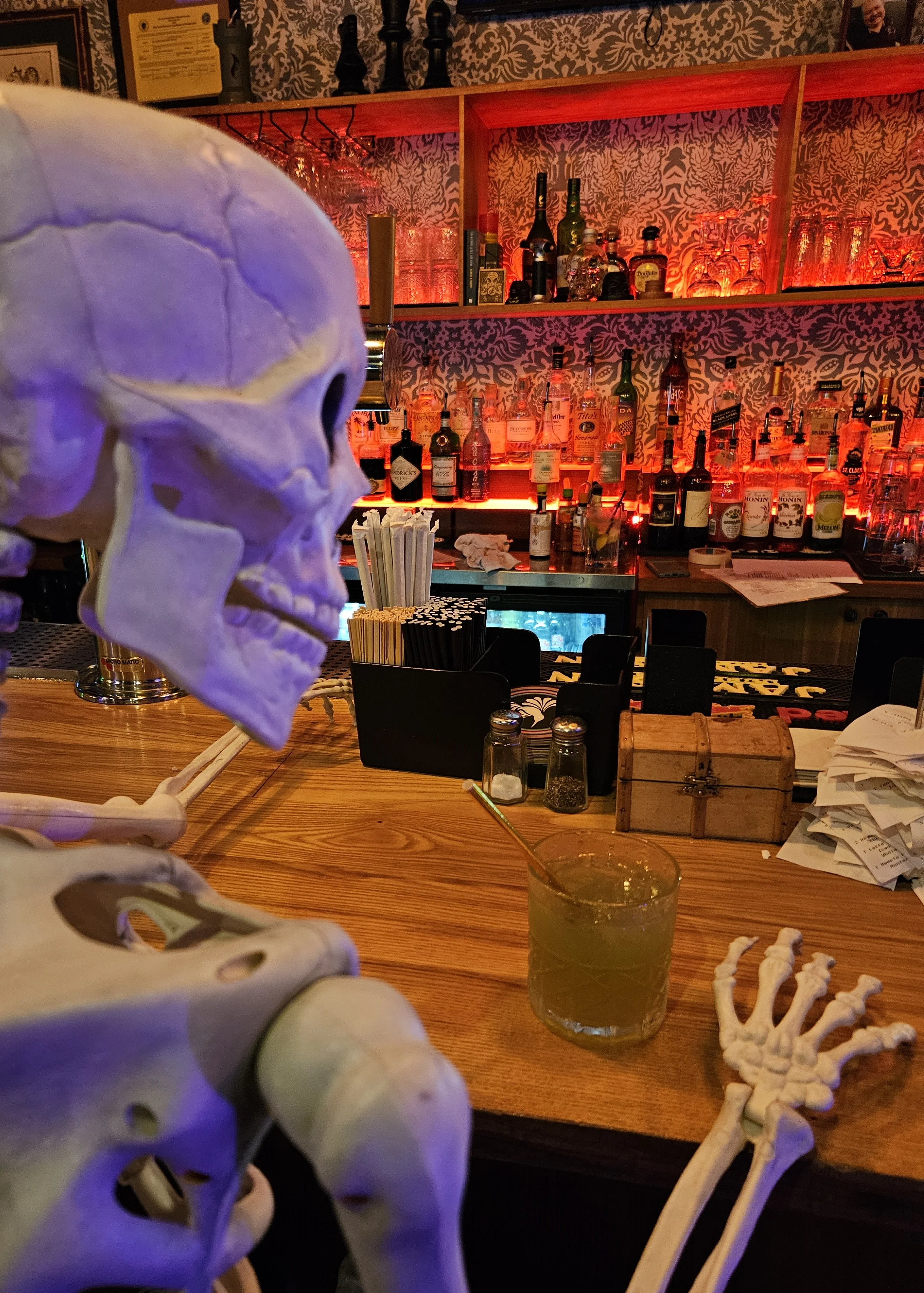 Skeleton enjoying a cocktail at a vibrant bar