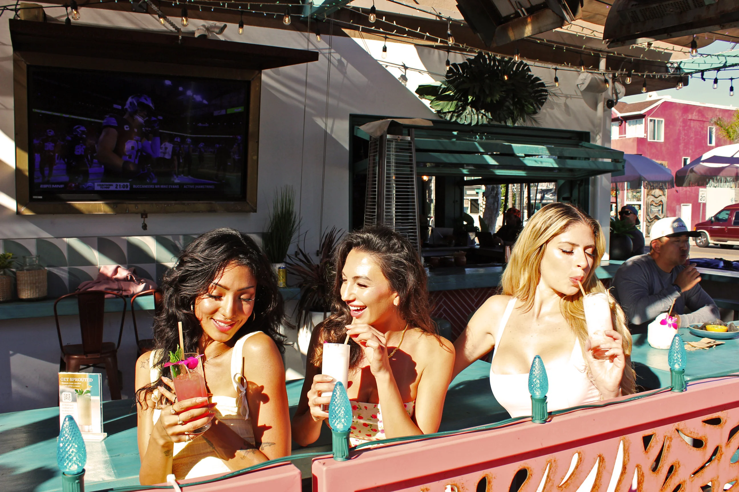 Three friends enjoying tropical cocktails at a vibrant outdoor bar