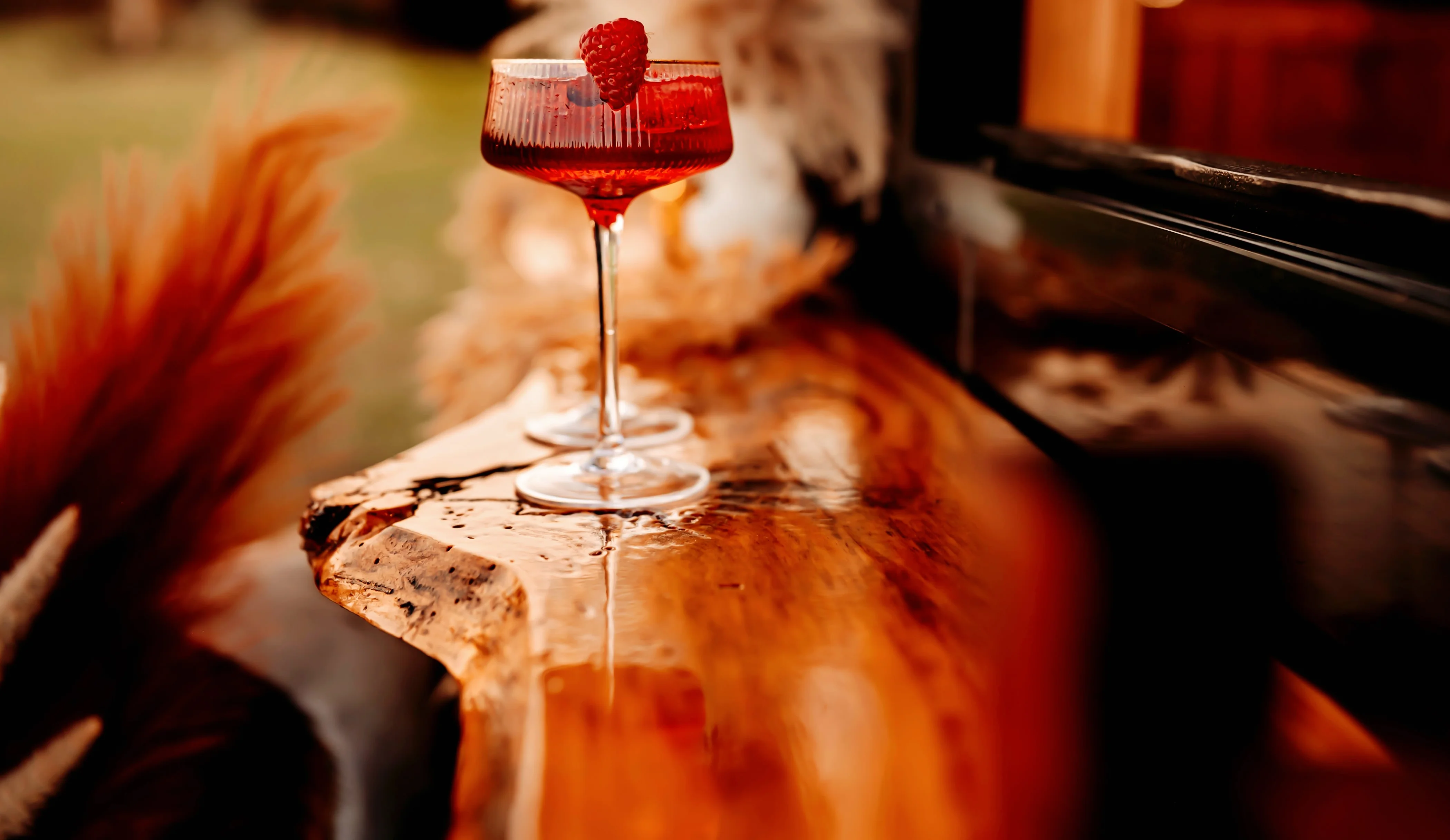 Elegant cocktail with raspberry garnish on a wooden bar