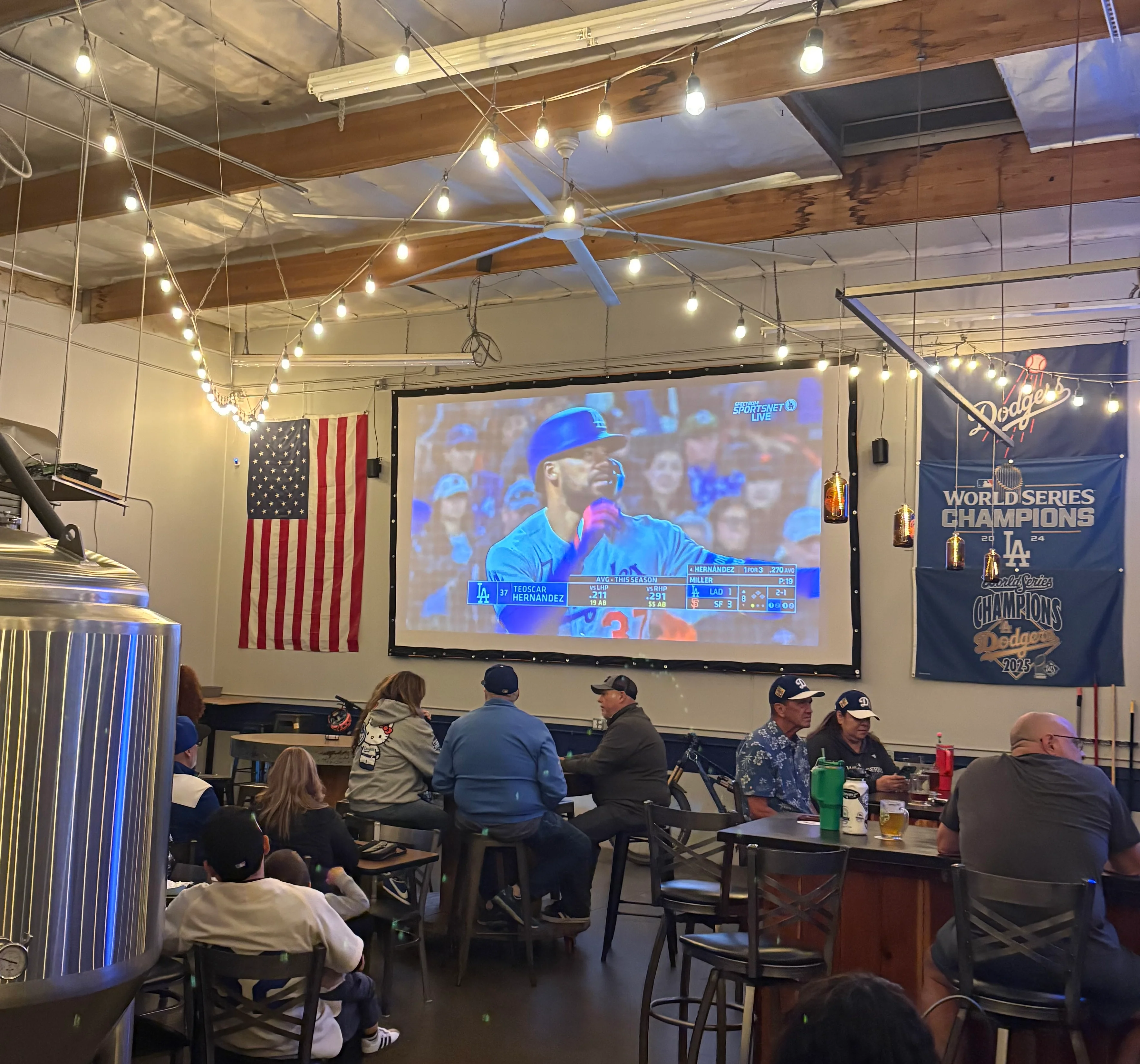 Cozy brewery interior with patrons watching a game on a large screen
