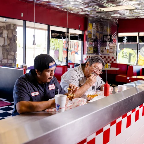 Two diners enjoying burgers in a retro diner setting