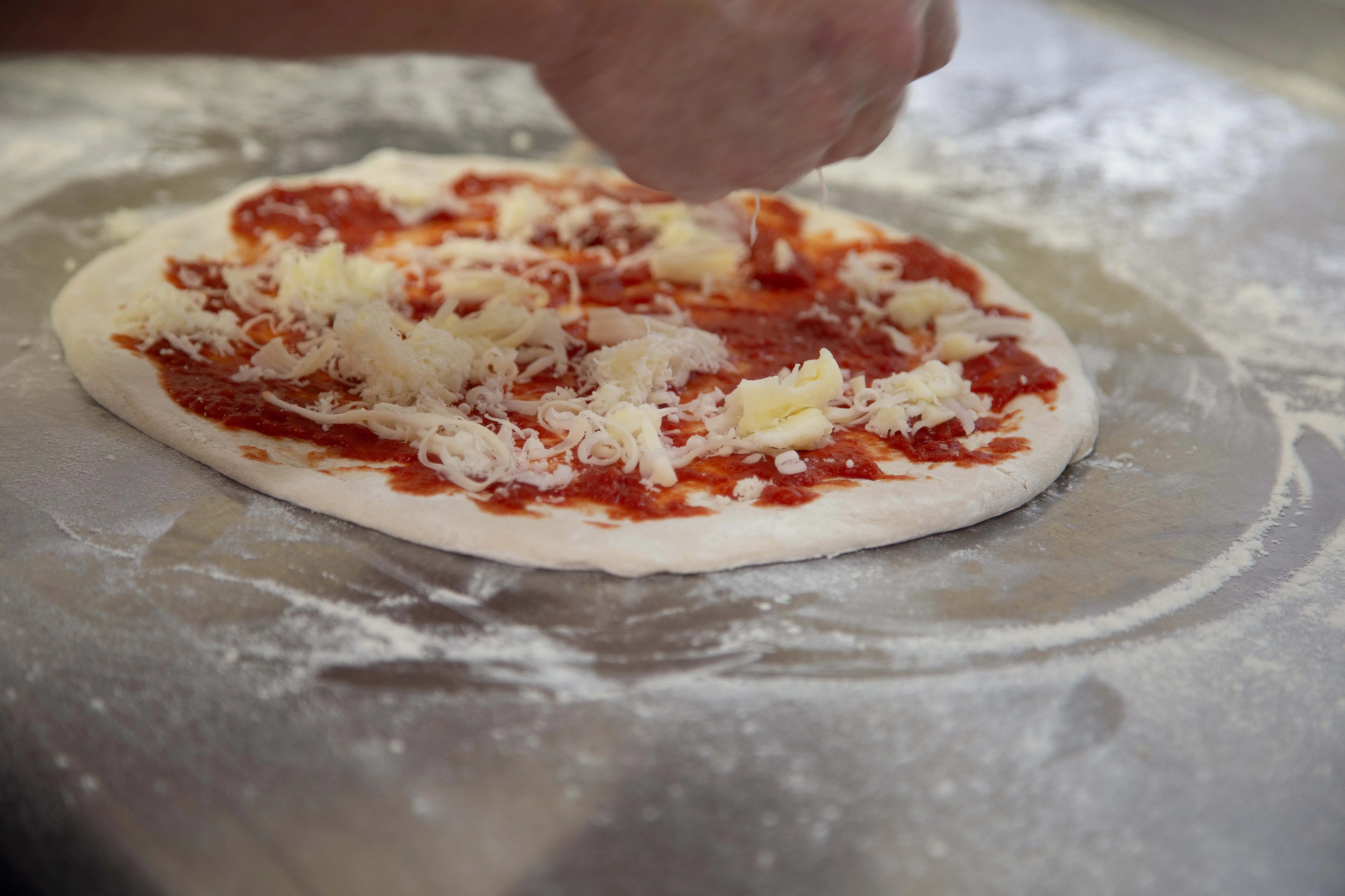 Preparing a Margherita pizza with tomato sauce and cheese