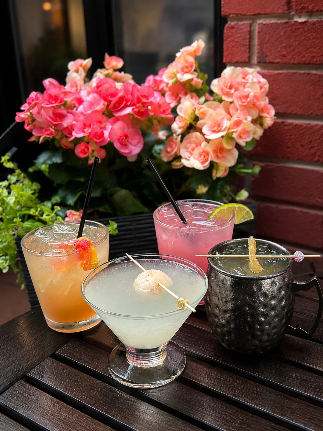 Colorful cocktails served on a wooden table with flowers in the background