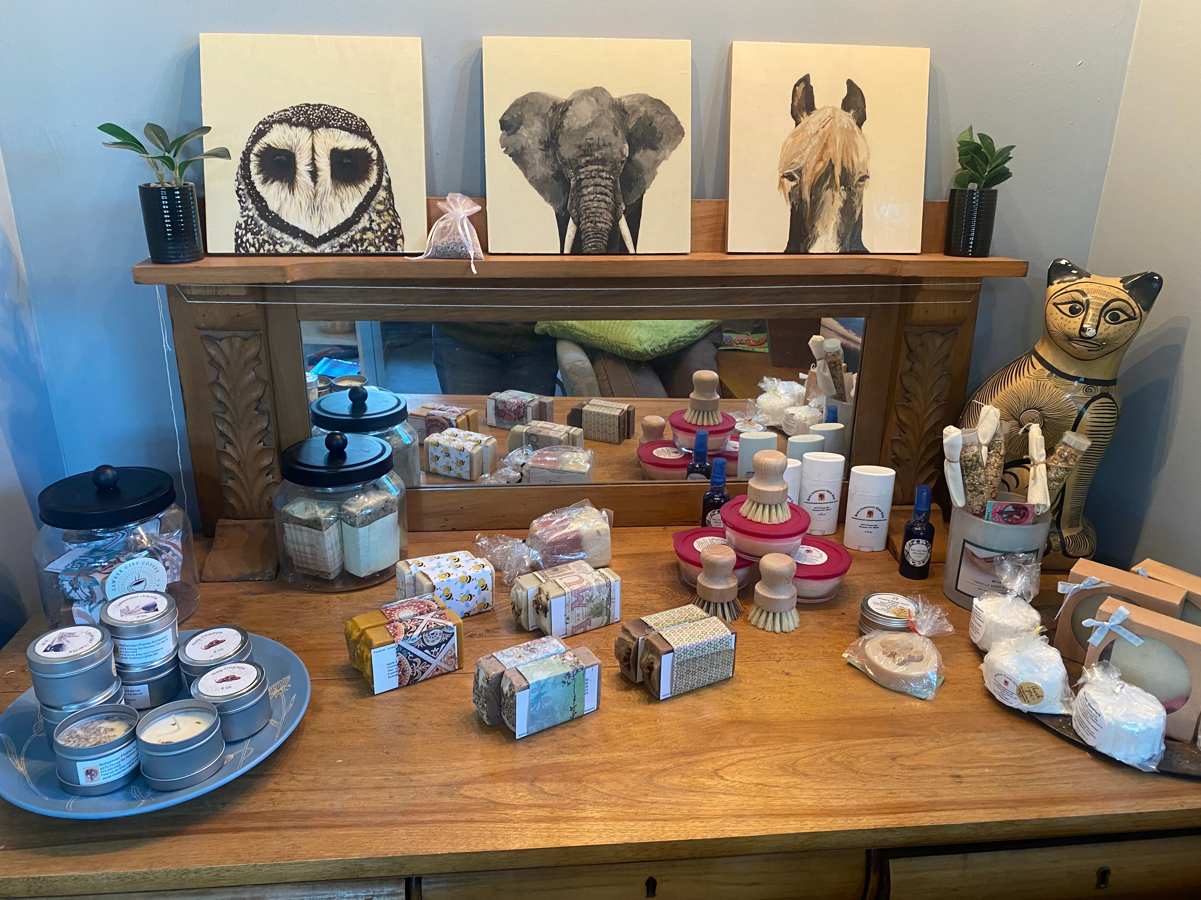 Display of handmade soaps and candles on a wooden dresser