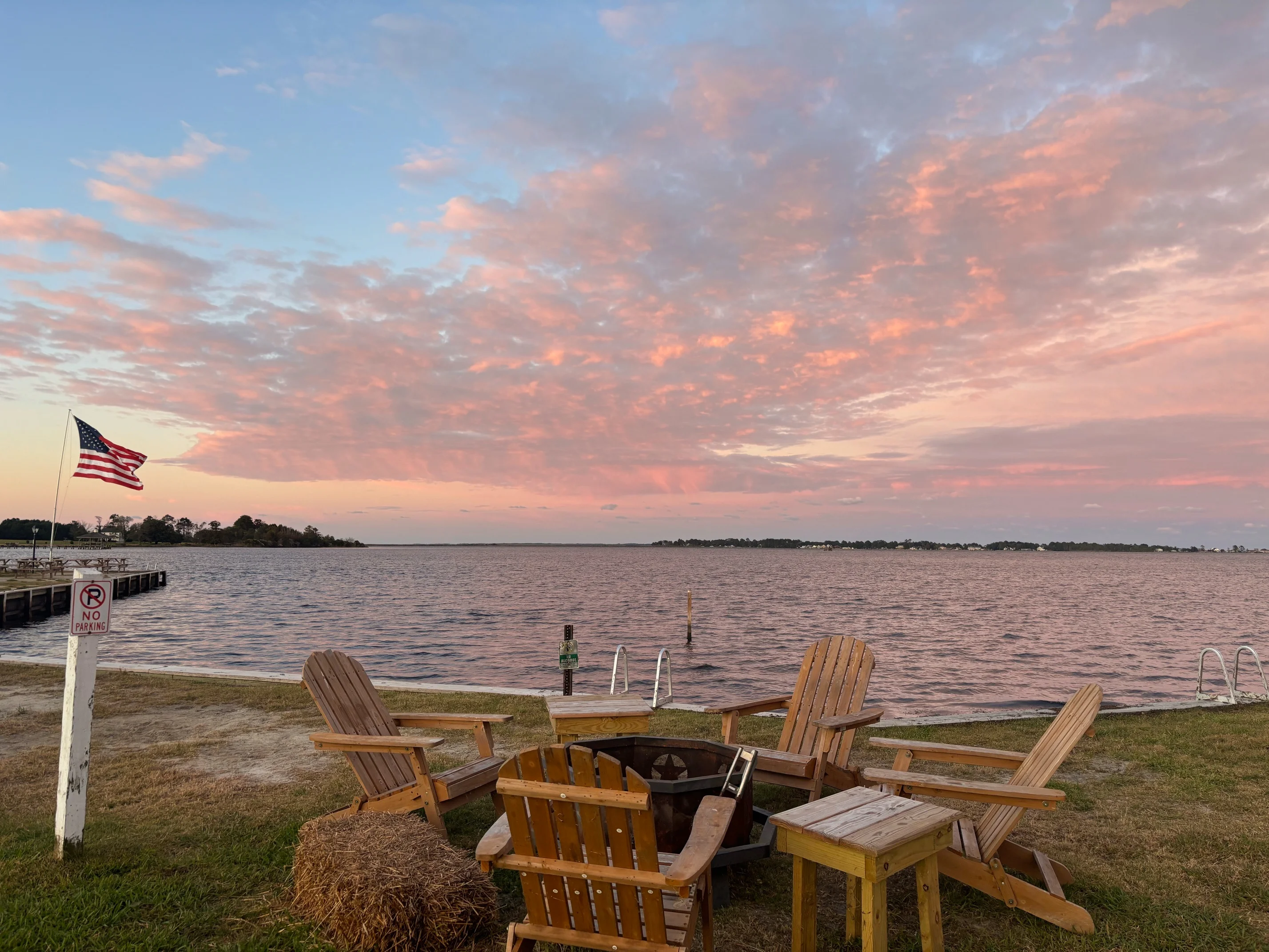 Scenic waterfront view with chairs and sunset sky