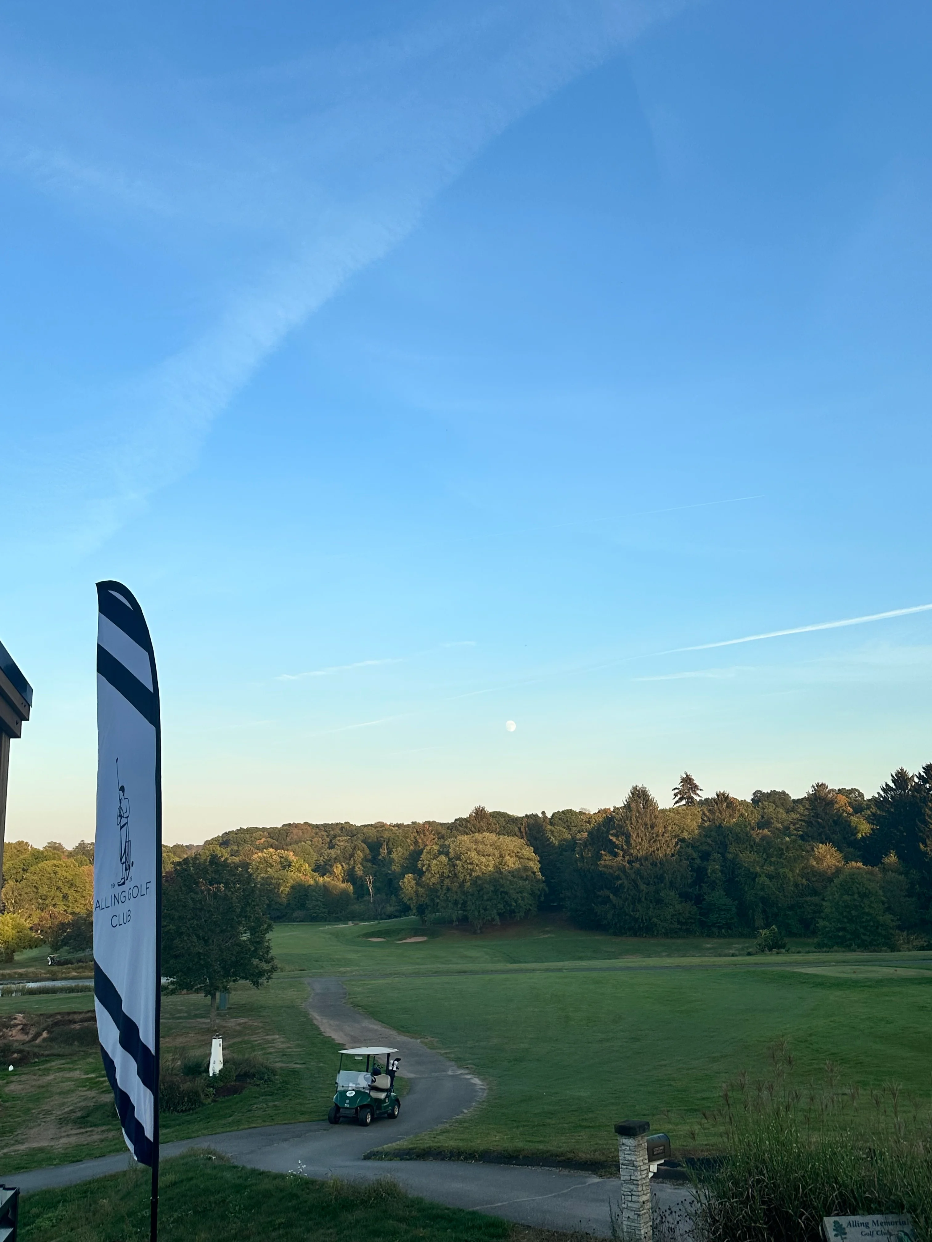 Scenic view of a golf course at sunrise with a flag in the foreground