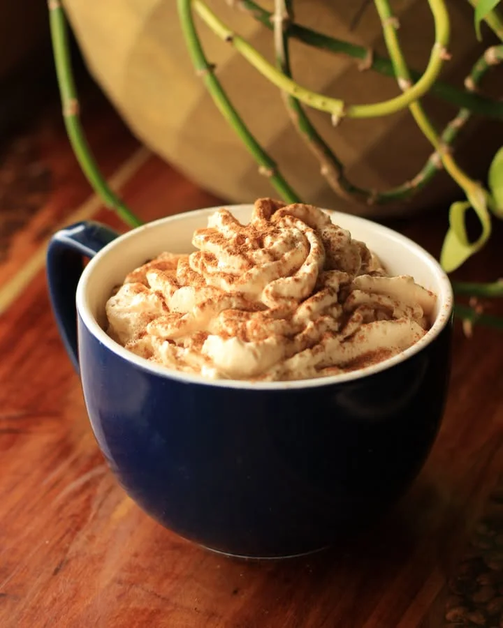 Creamy cappuccino topped with whipped cream and cocoa