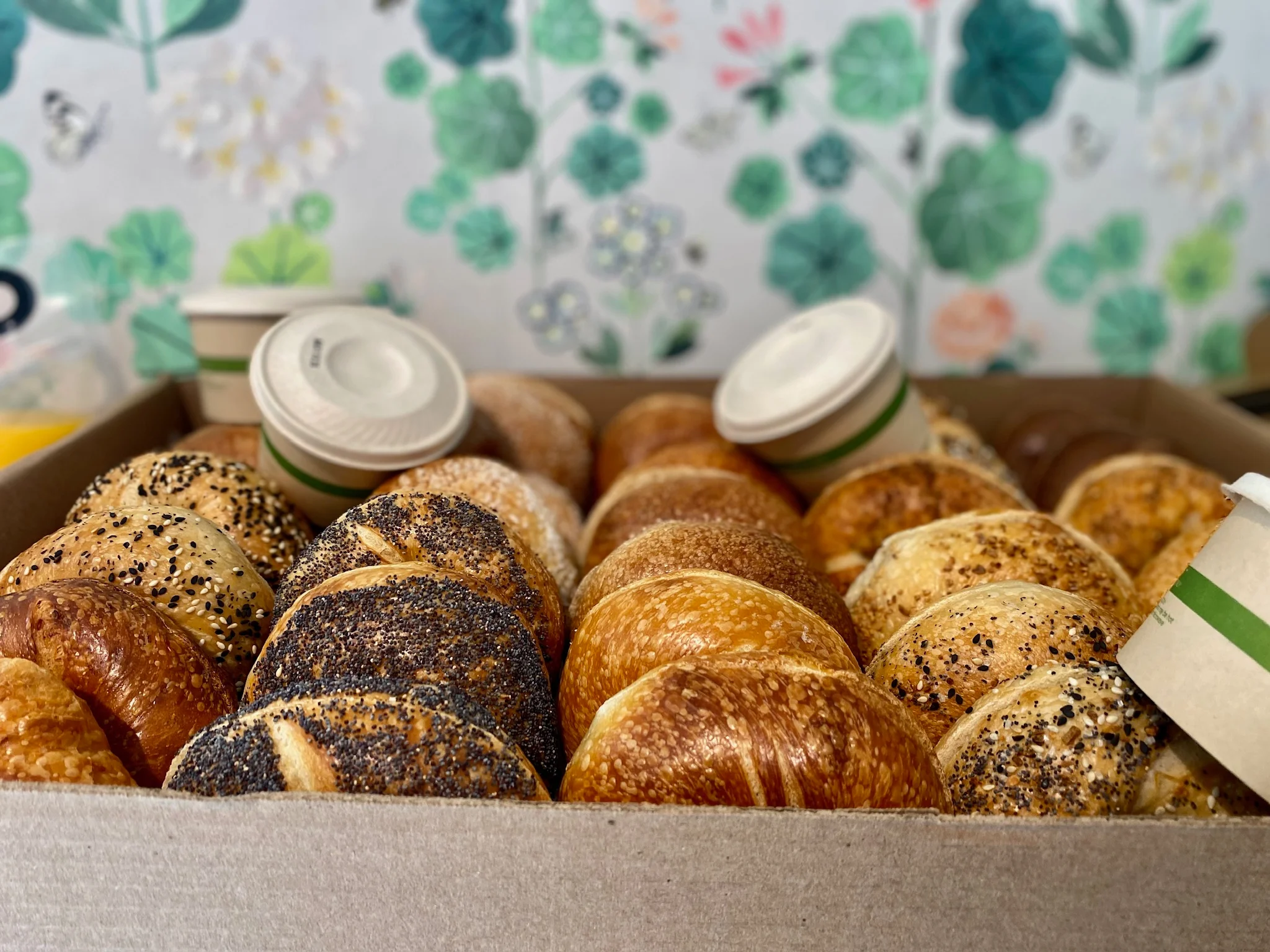 Assorted bagels in a box with coffee cups