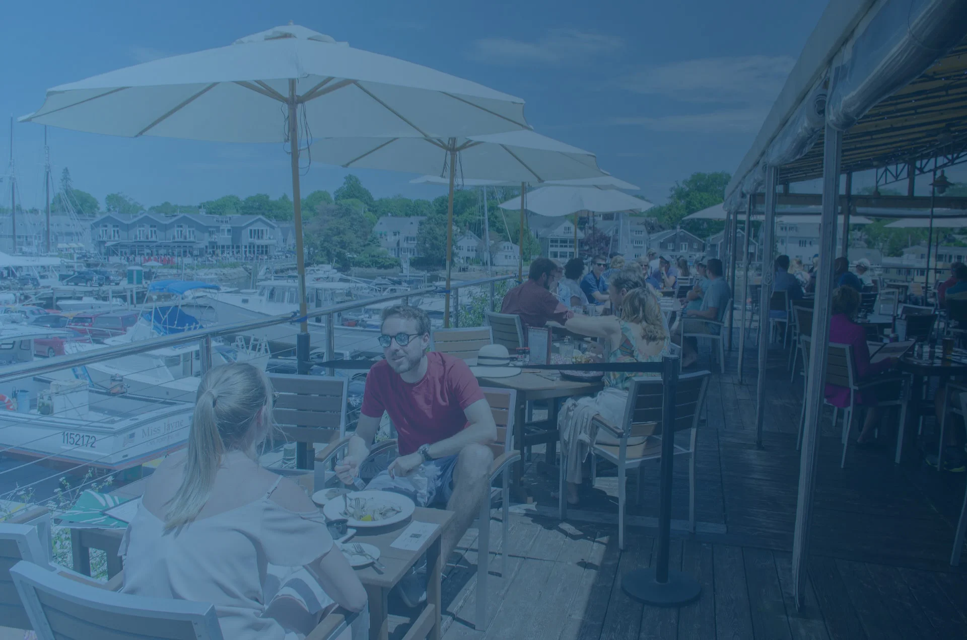 Outdoor dining area overlooking a marina with umbrellas