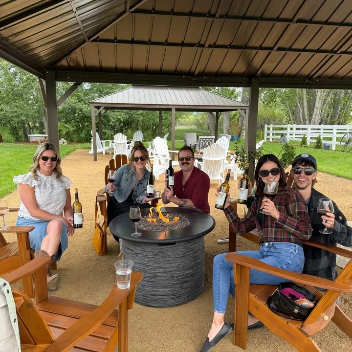 Group enjoying wine by a fire pit in a cozy outdoor setting