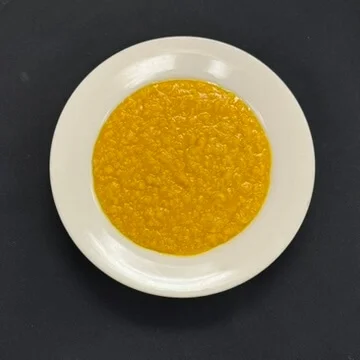A vibrant yellow sauce served on a white plate, featuring a smooth texture.