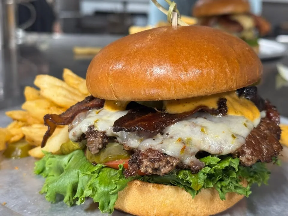 Delicious gourmet burger with fresh toppings on a wooden table.