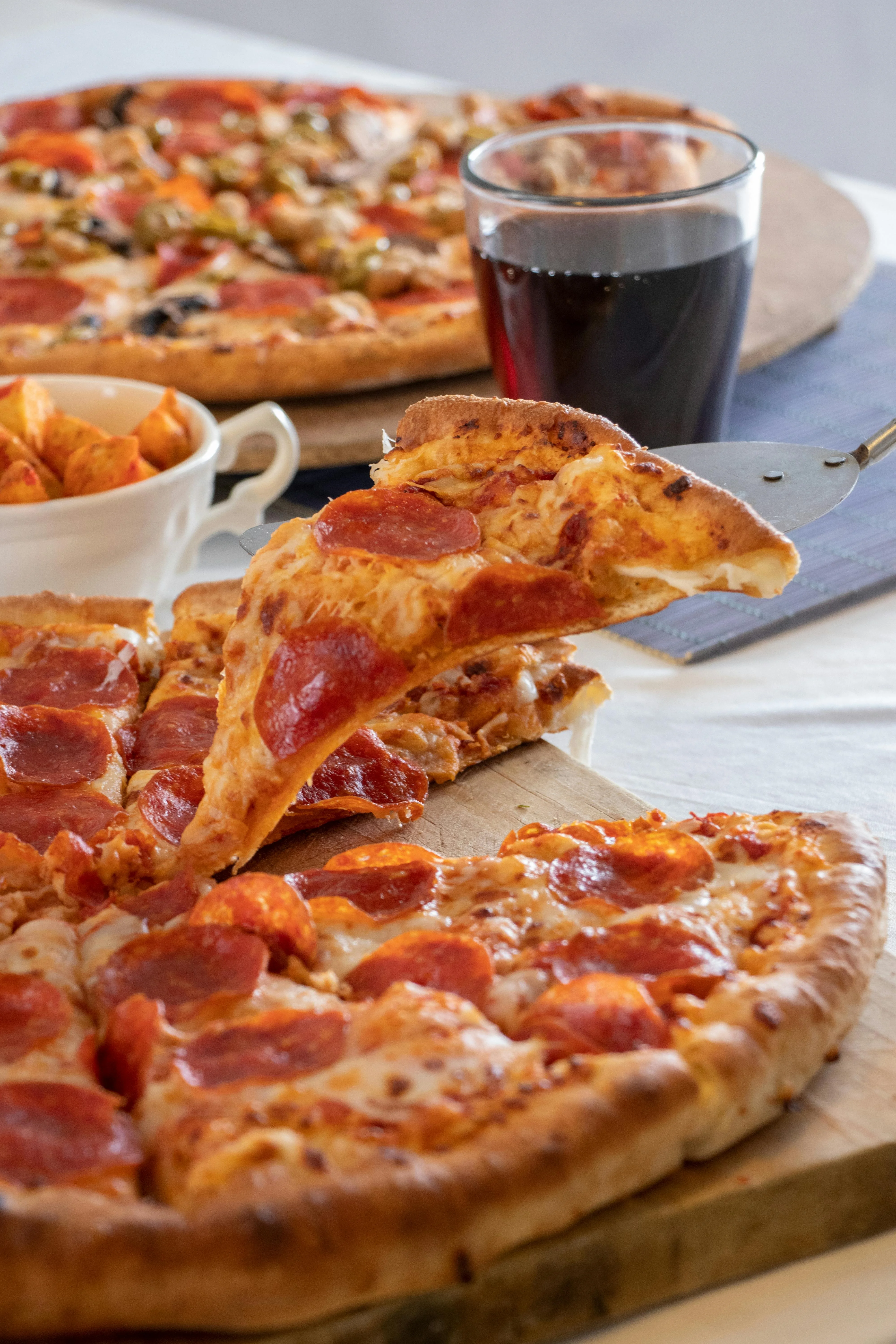 Delicious pepperoni pizza slice being served with drinks and snacks.