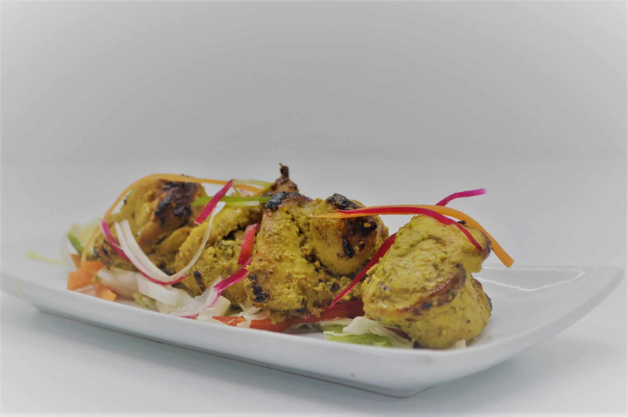 Grilled chicken tikka served on a bed of fresh salad