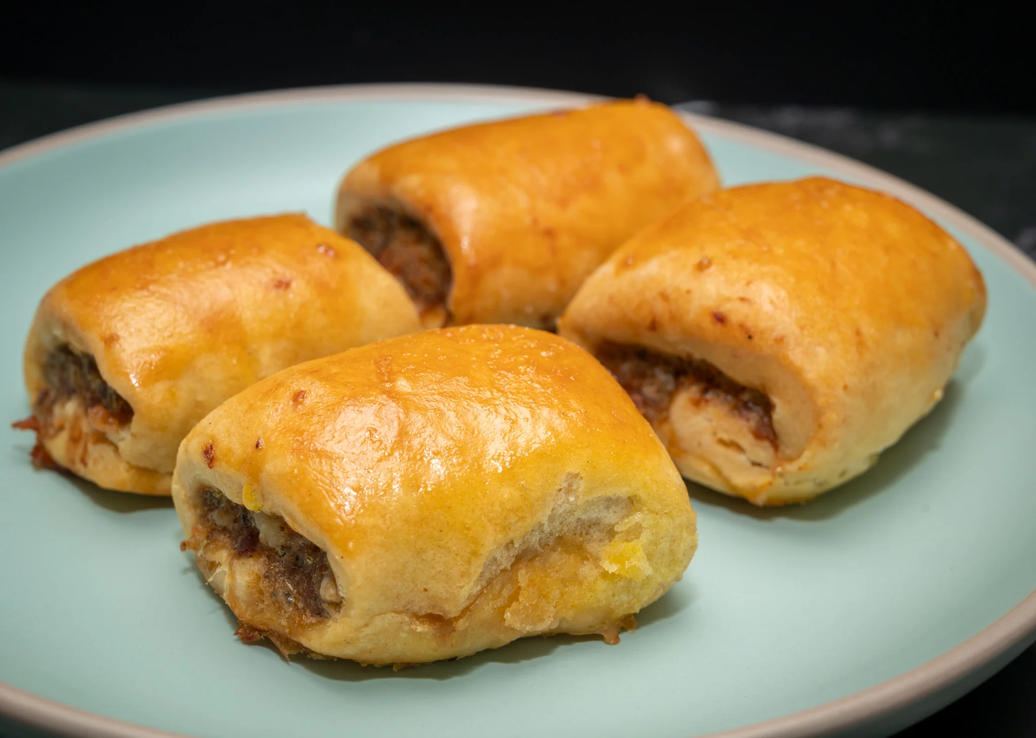 Golden-brown sausage rolls arranged on a white plate.