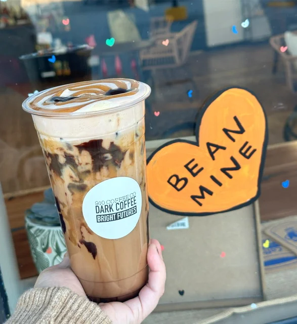 Iced coffee drink with chocolate drizzle in front of a colorful window