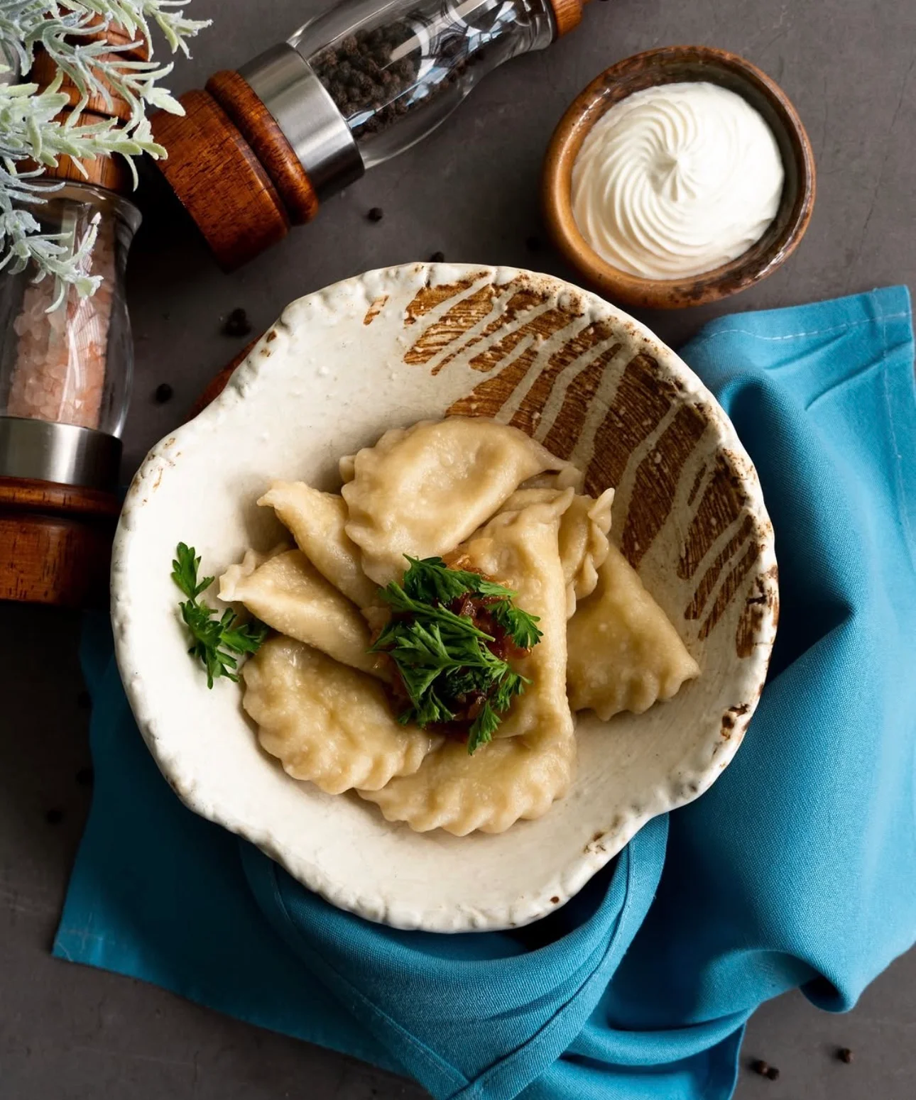 Plate of Ukrainian pierogi with sour cream and herbs