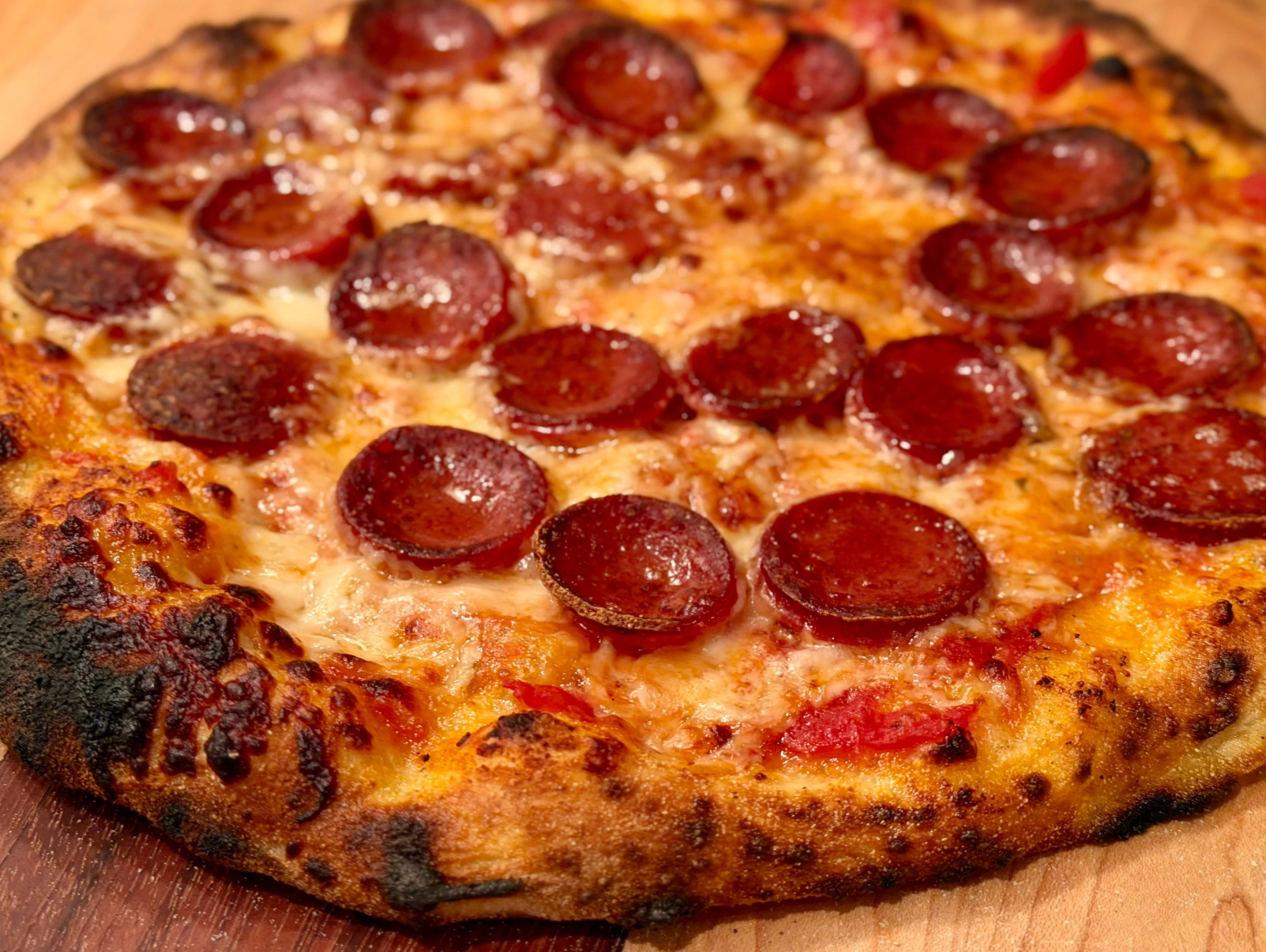 A savory pizza topped with pepperoni slices on a golden crust, served on a wooden surface.