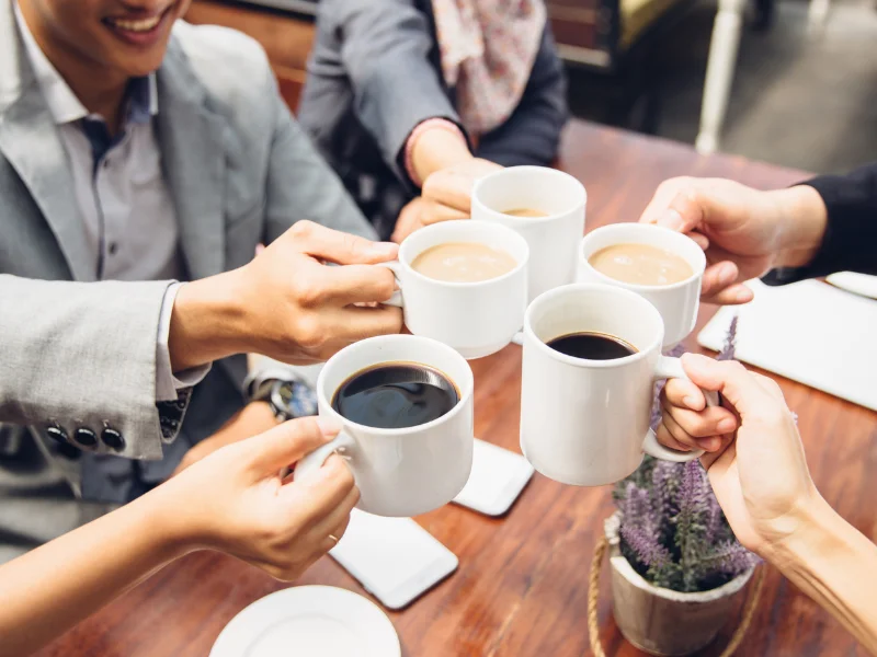Group toasting with coffee cups at a cafe