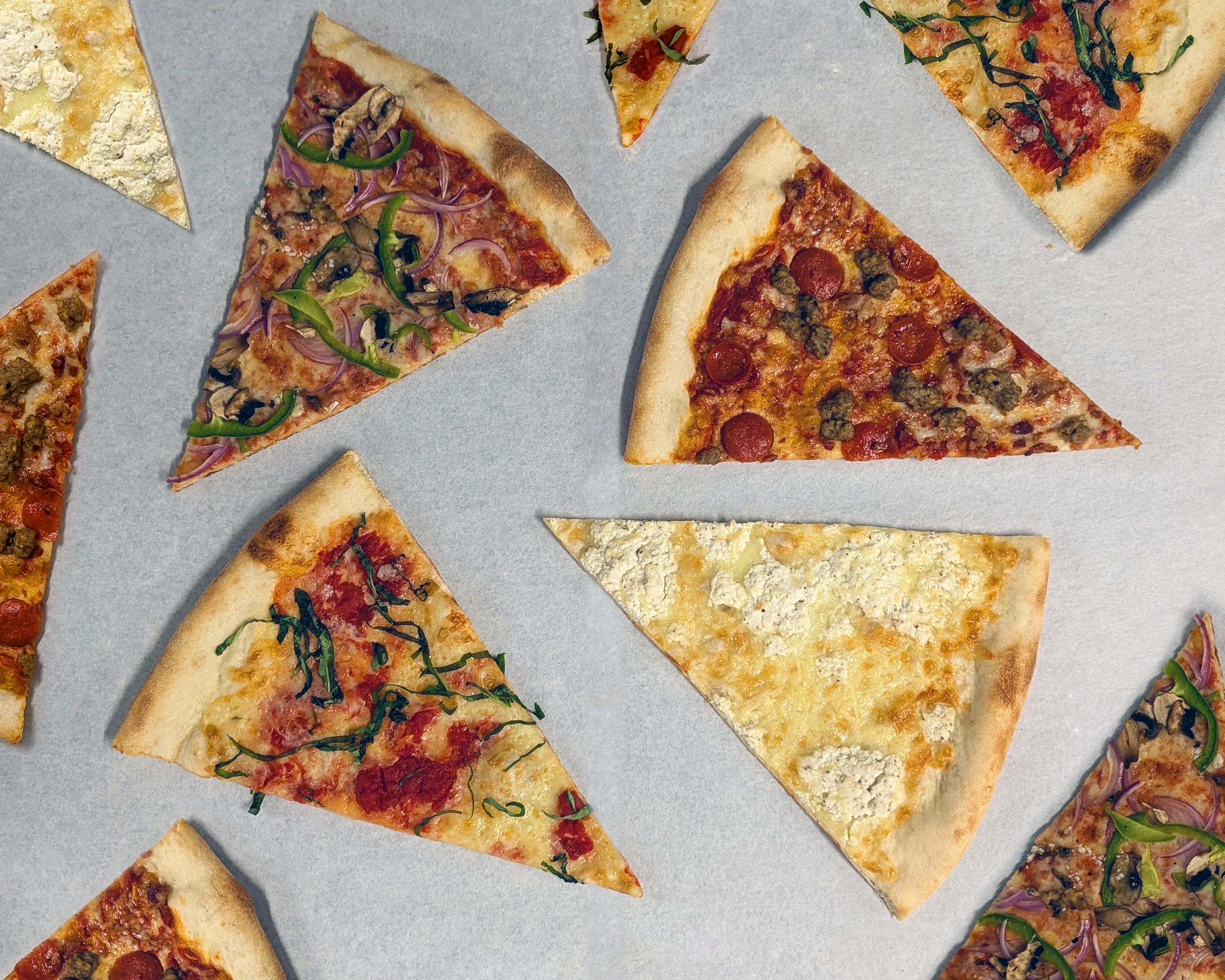 Variety of pizza slices including pepperoni and vegetarian options