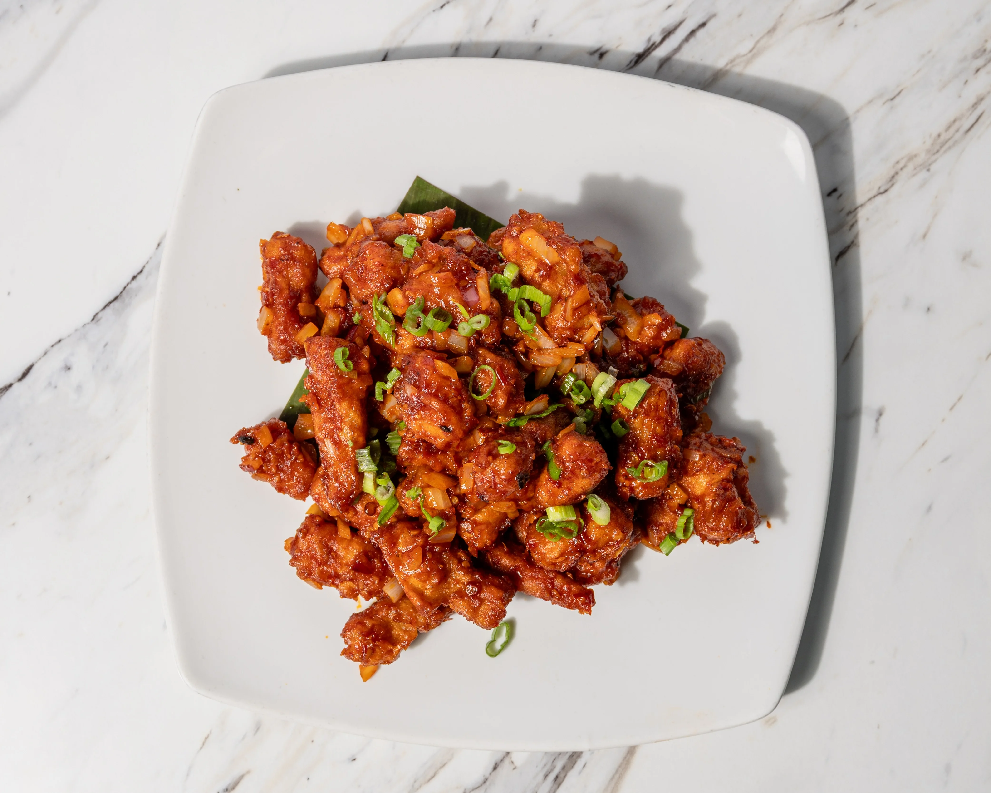 Crispy Korean sweet and spicy chicken dish garnished with green onions