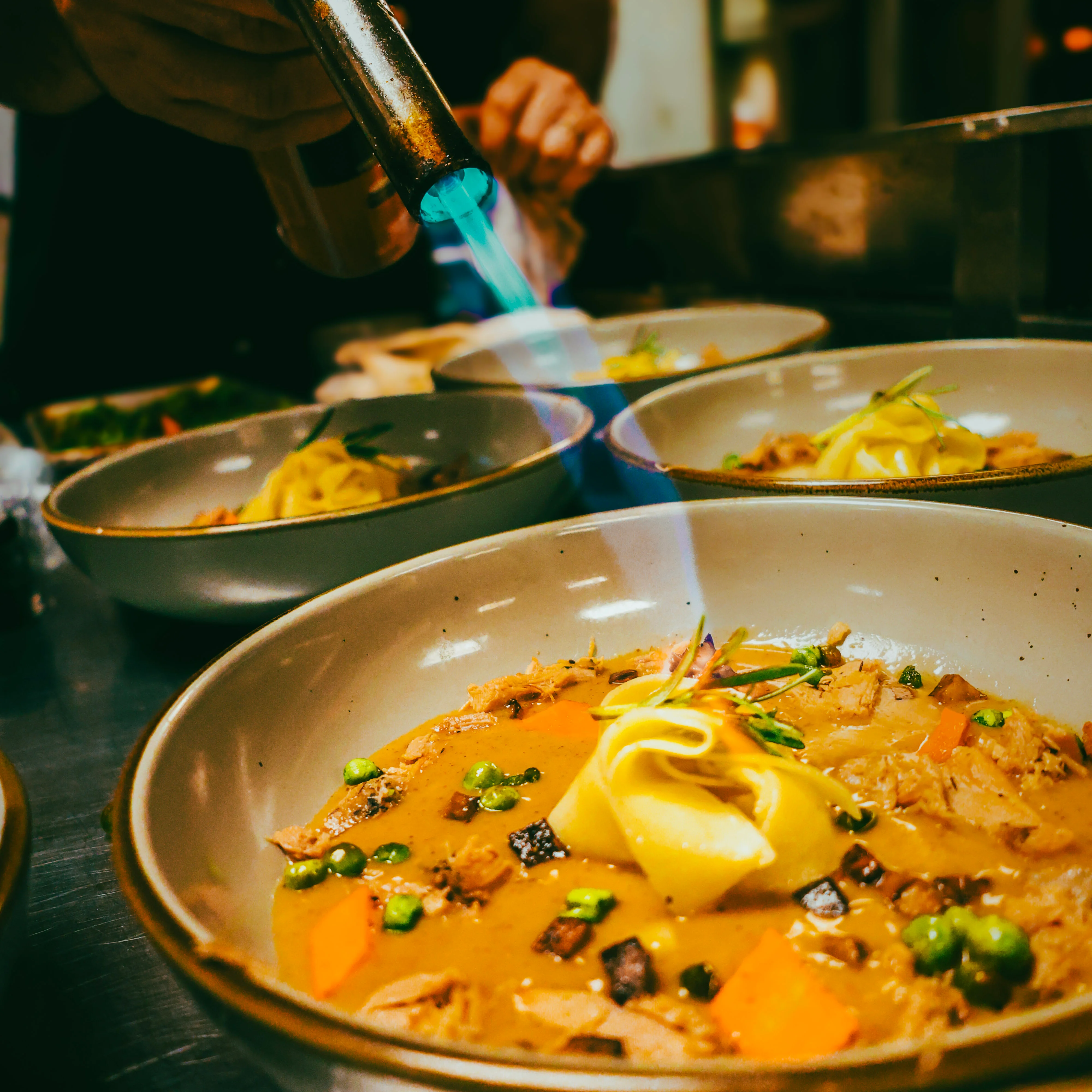 Chef using a torch on Asian-style ramen bowl