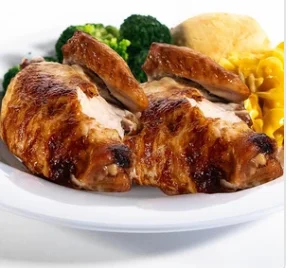 A plate featuring roasted chicken with a side of broccoli, a biscuit, and macaroni.