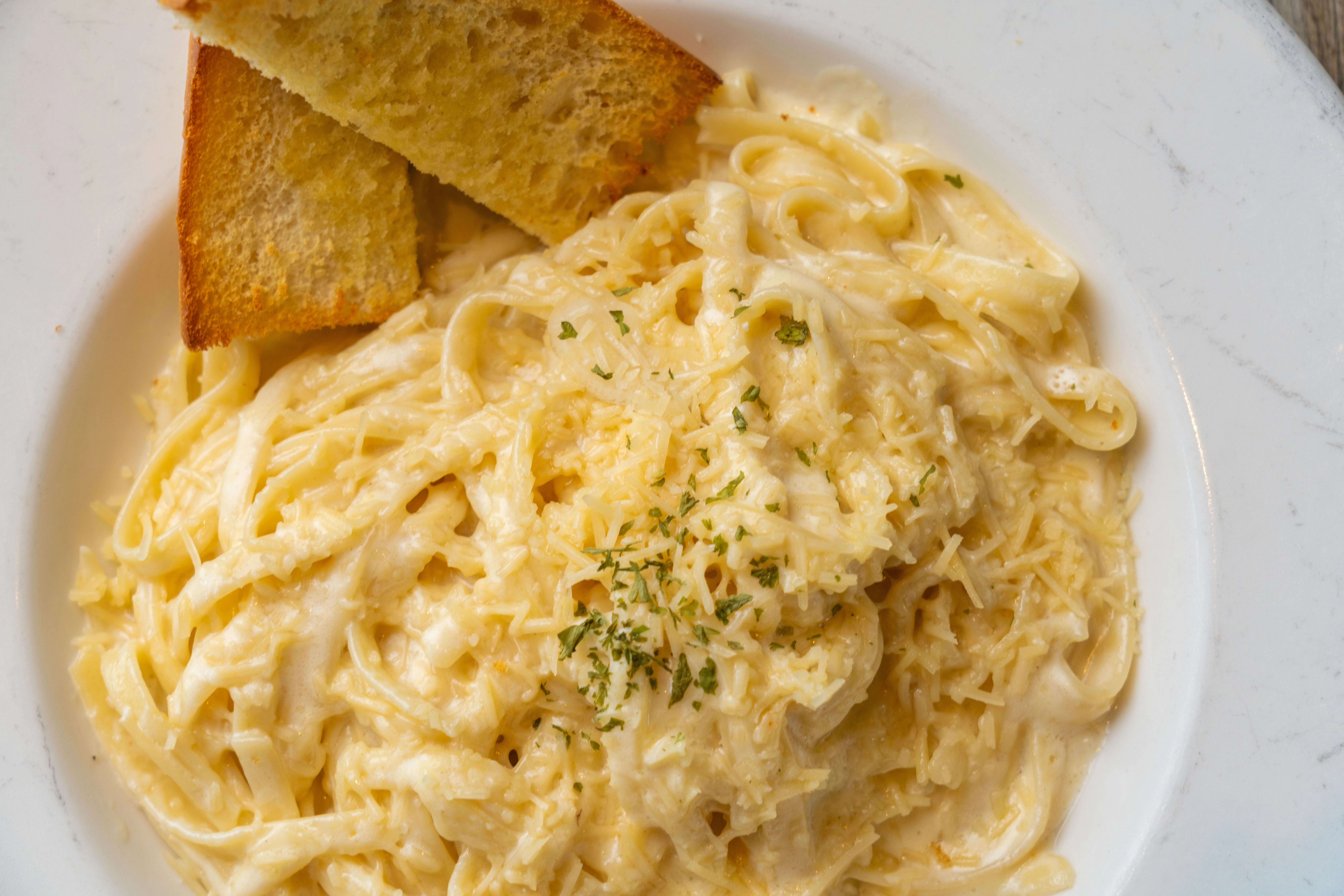 Creamy Alfredo pasta dish garnished with parsley and served in a bowl.