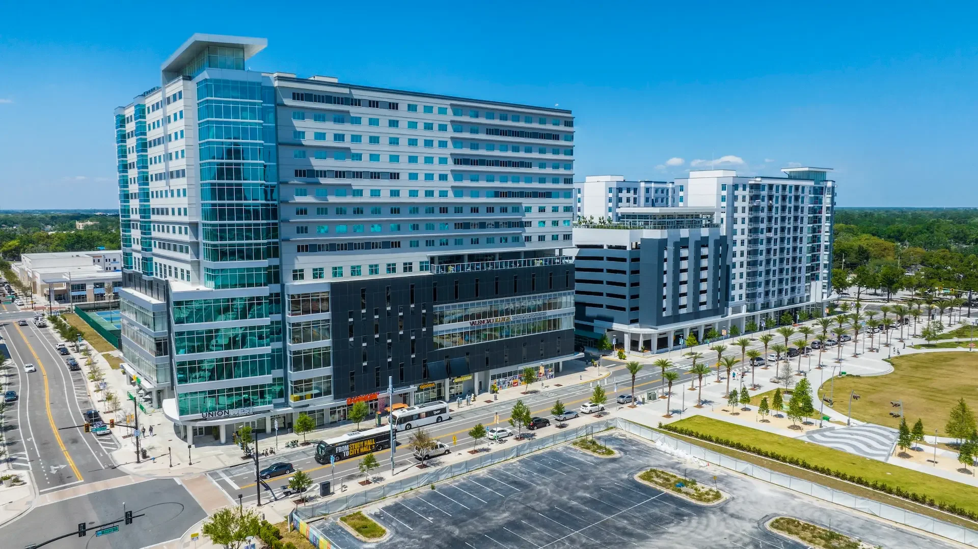 Modern urban buildings with glass facades and palm-lined streets