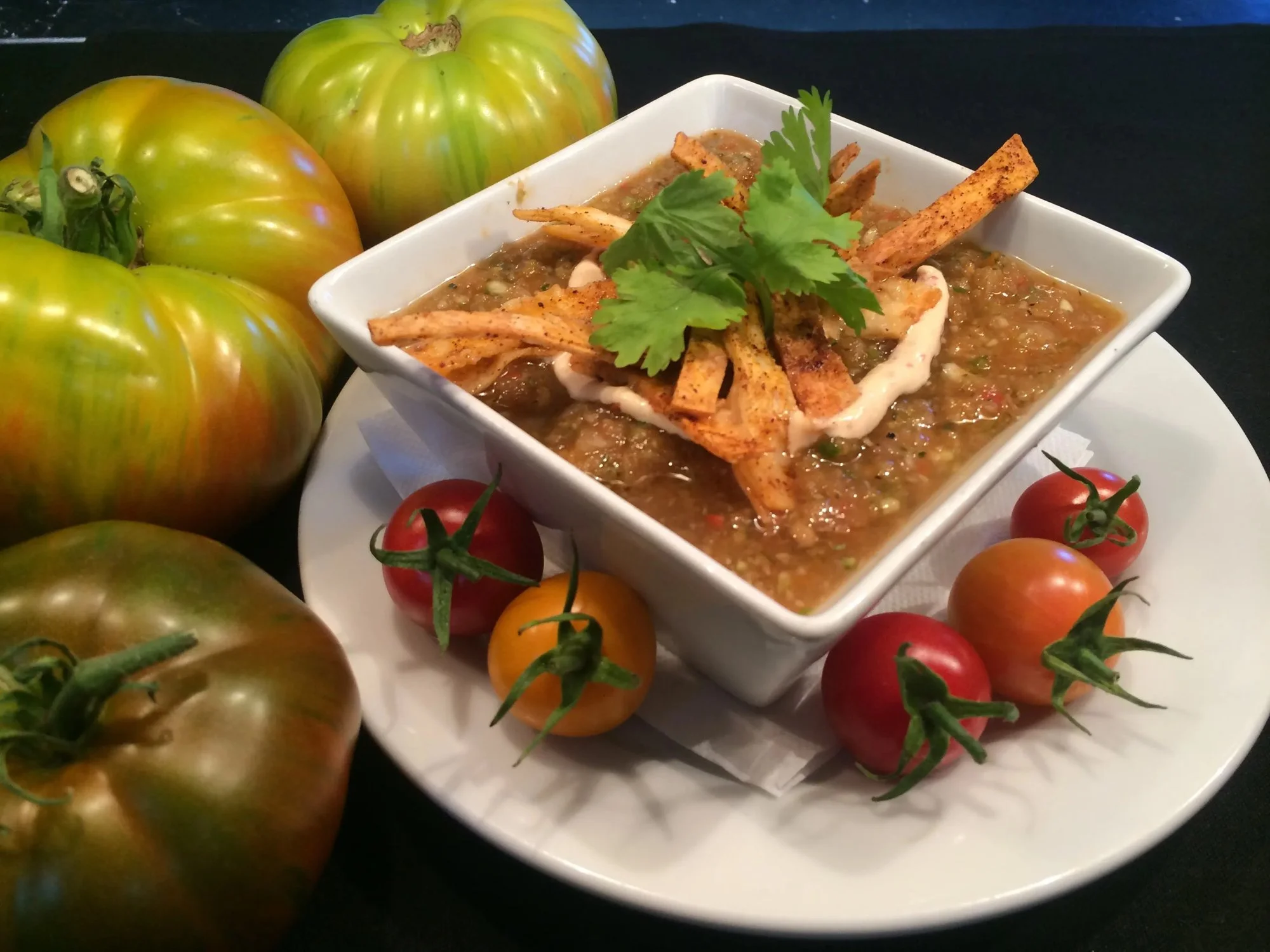A bowl of soup with heirloom tomatoes
