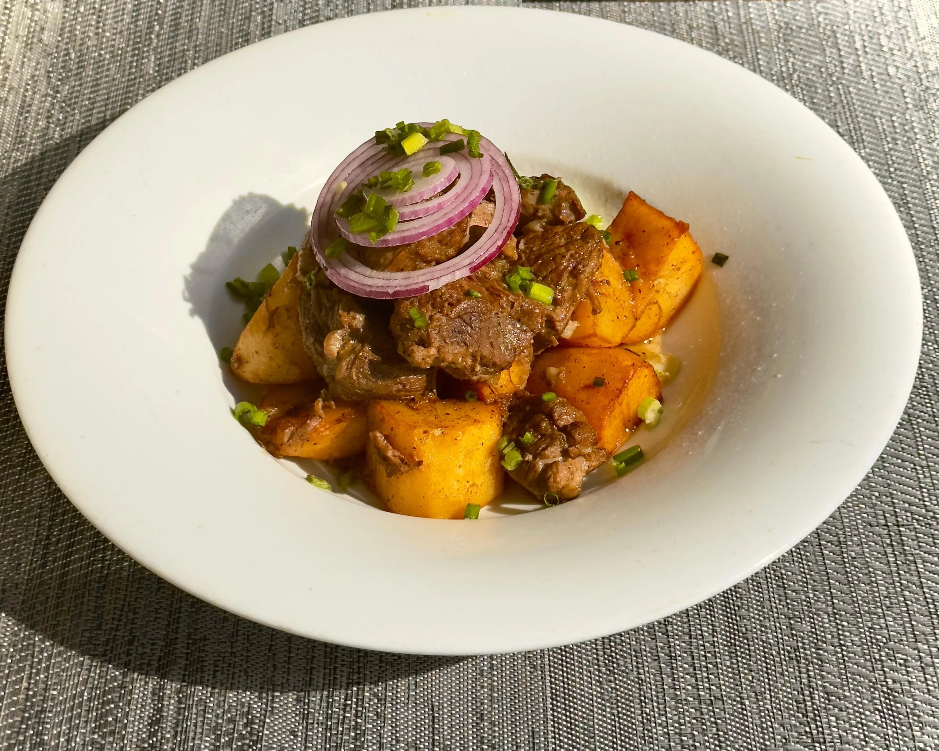 Savory Ghanaian beef and yam stew garnished with onions