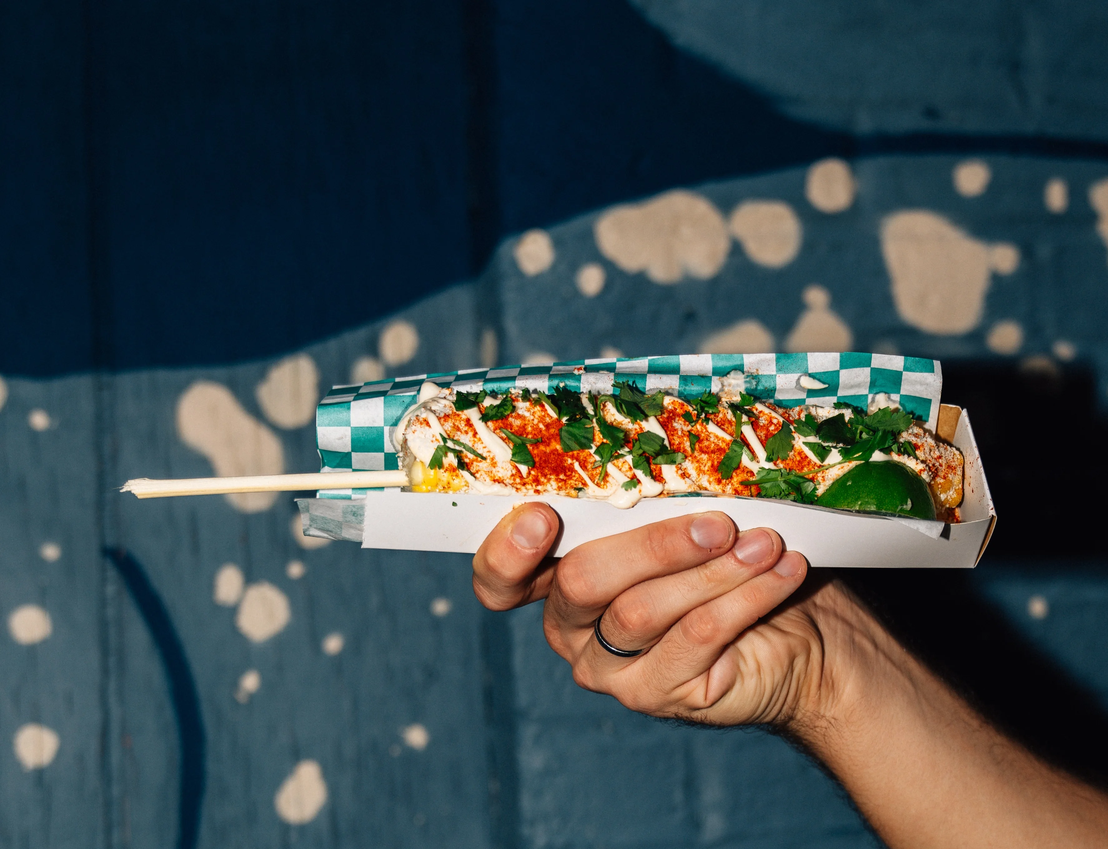 Mexican elote served on a stick with toppings