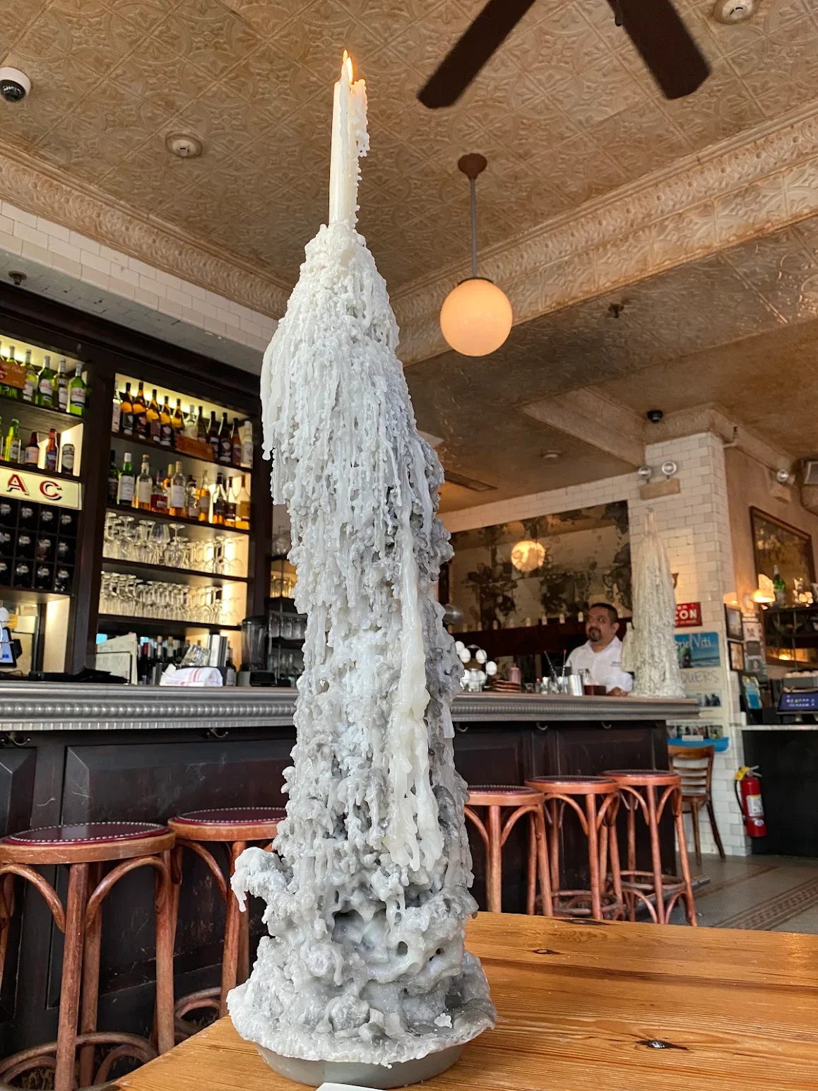 Unique candle sculpture with wax drippings in a stylish restaurant interior