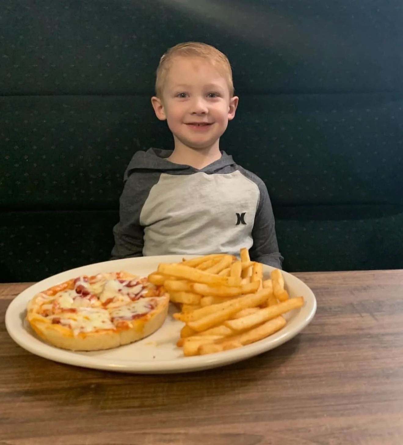 Child enjoying personal pizza and fries at a restaurant