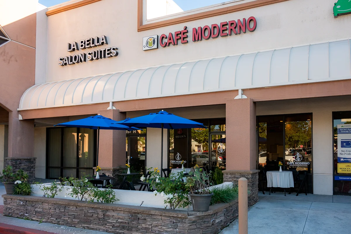 Exterior view of Café Moderno with outdoor seating and blue umbrellas