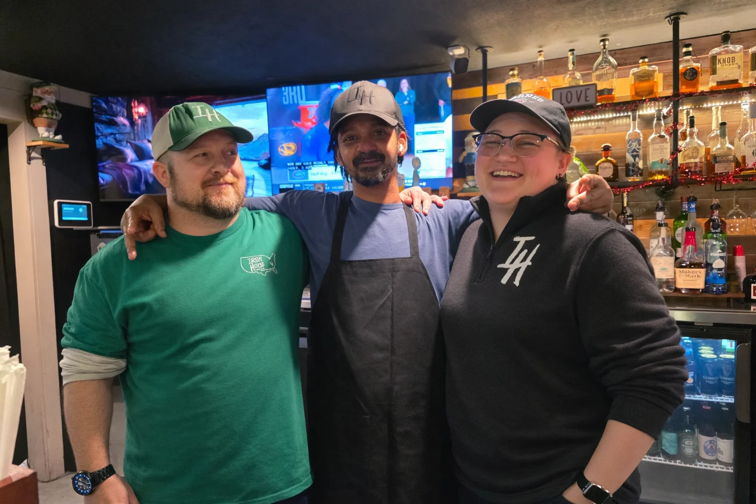 Friendly restaurant staff posing together behind the bar