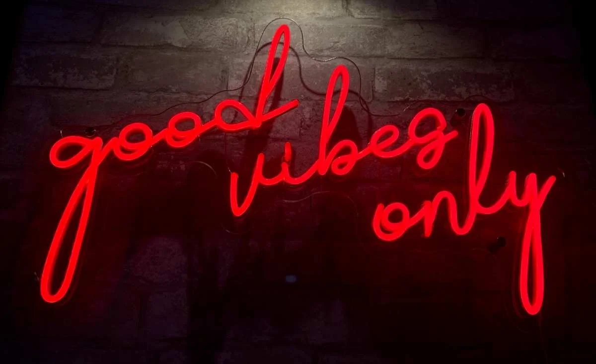 Neon sign reading 'good vibes only' in a cozy restaurant