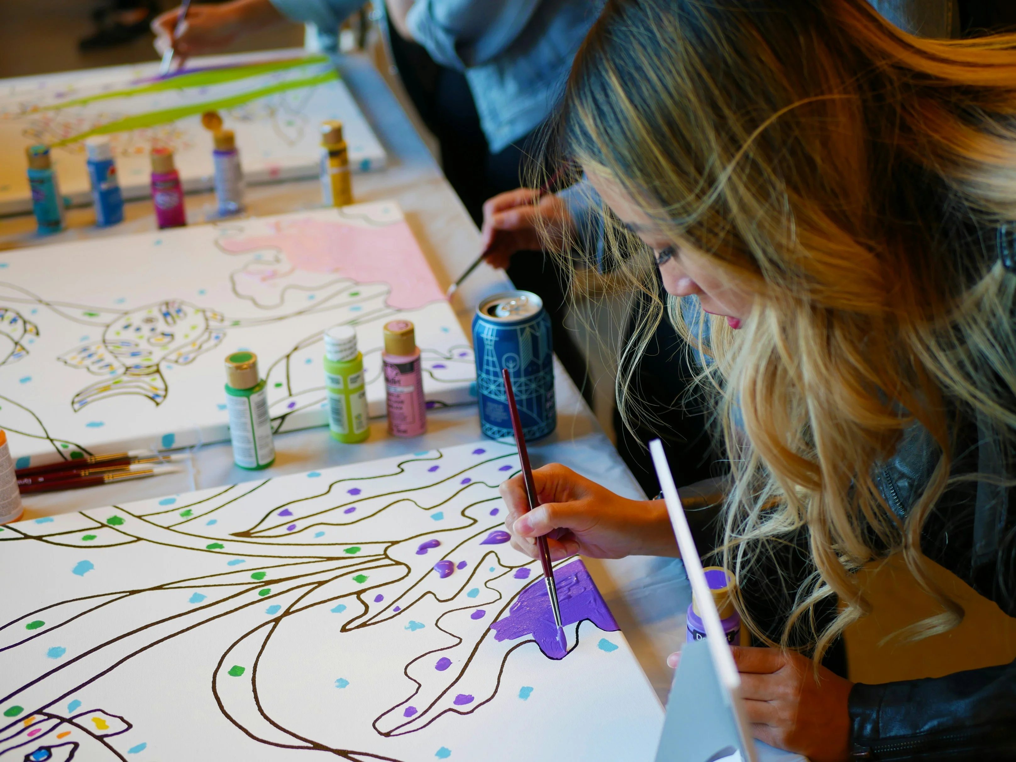 Participants painting on canvases at a creative workshop
