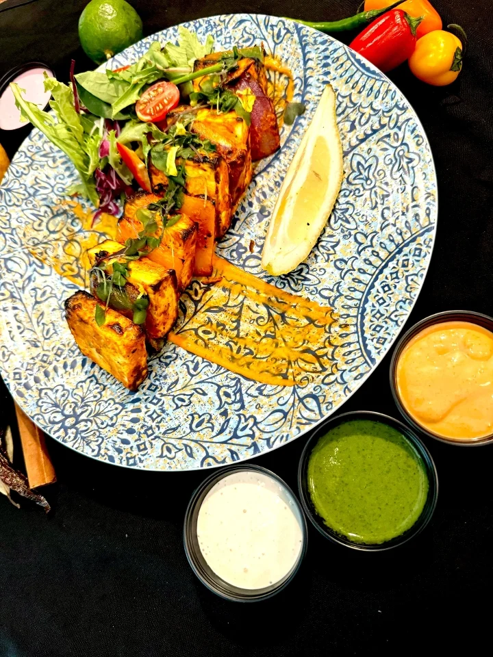 Grilled paneer tikka with vibrant sauces and fresh salad