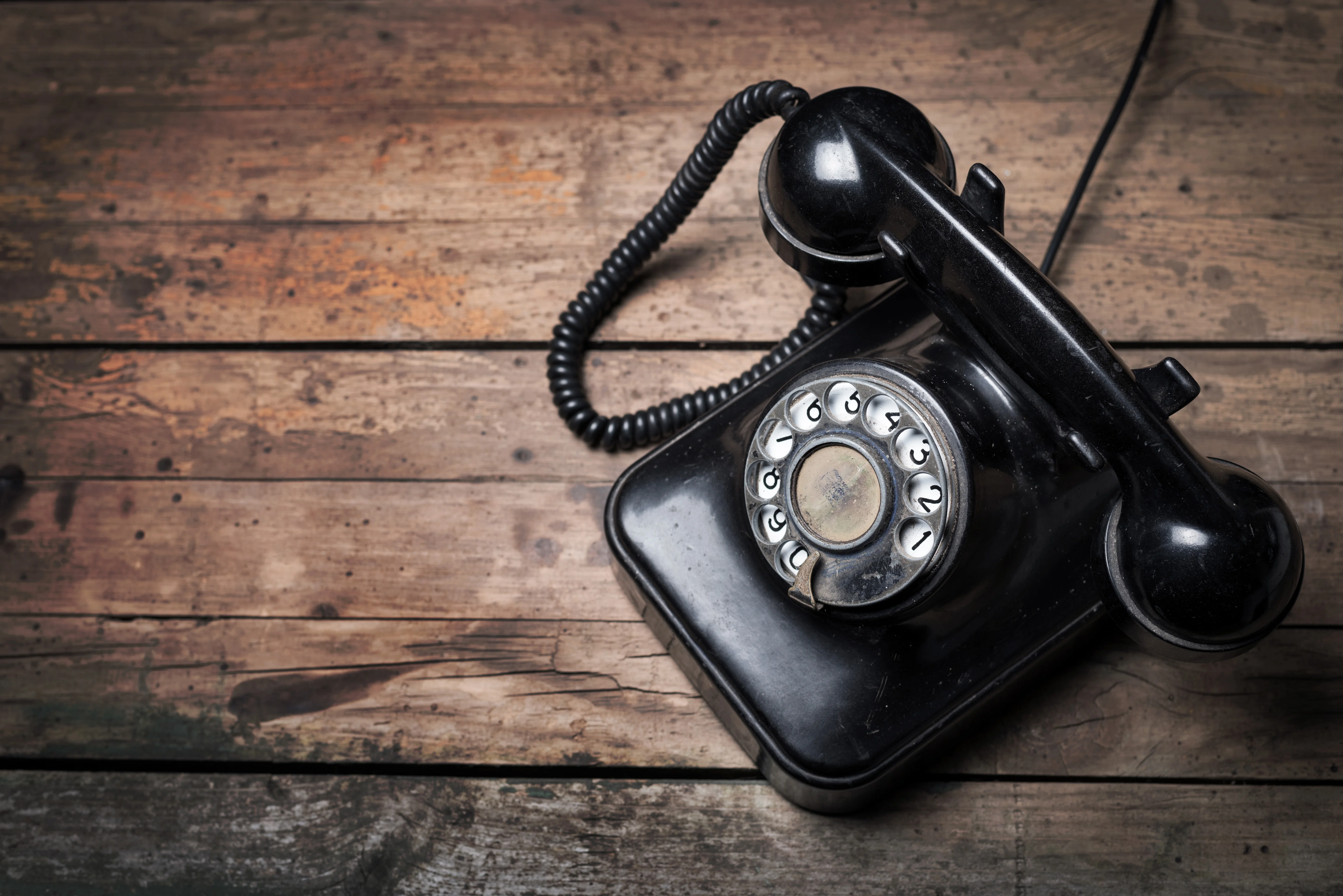 Vintage black rotary phone on wooden table