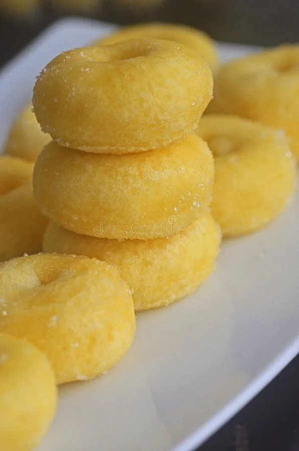 Delicious yellow mini donuts on a white plate